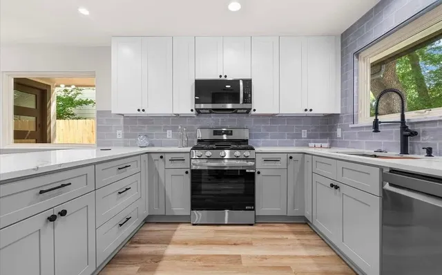 a kitchen with stainless steel appliances granite countertop a stove a sink and a microwave