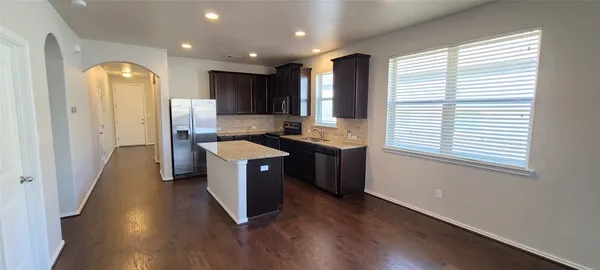 a kitchen with stainless steel appliances granite countertop a refrigerator a sink dishwasher a stove and a refrigerator with wooden floor