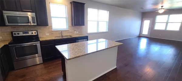 a kitchen with granite countertop a stove a sink and a microwave