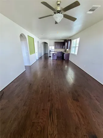 a view of an empty room with a window and wooden floor