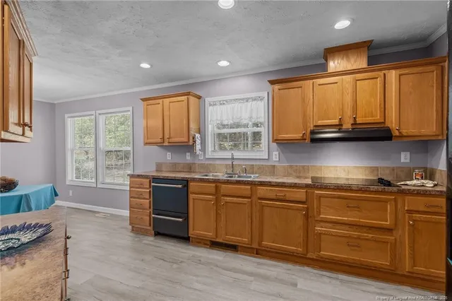 a kitchen with stainless steel appliances granite countertop wooden cabinets a sink and dishwasher with wooden floor