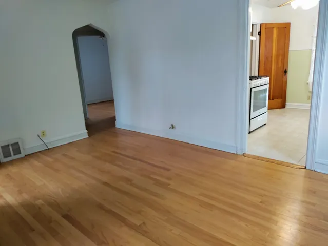 an empty room with wooden floor and a hallway
