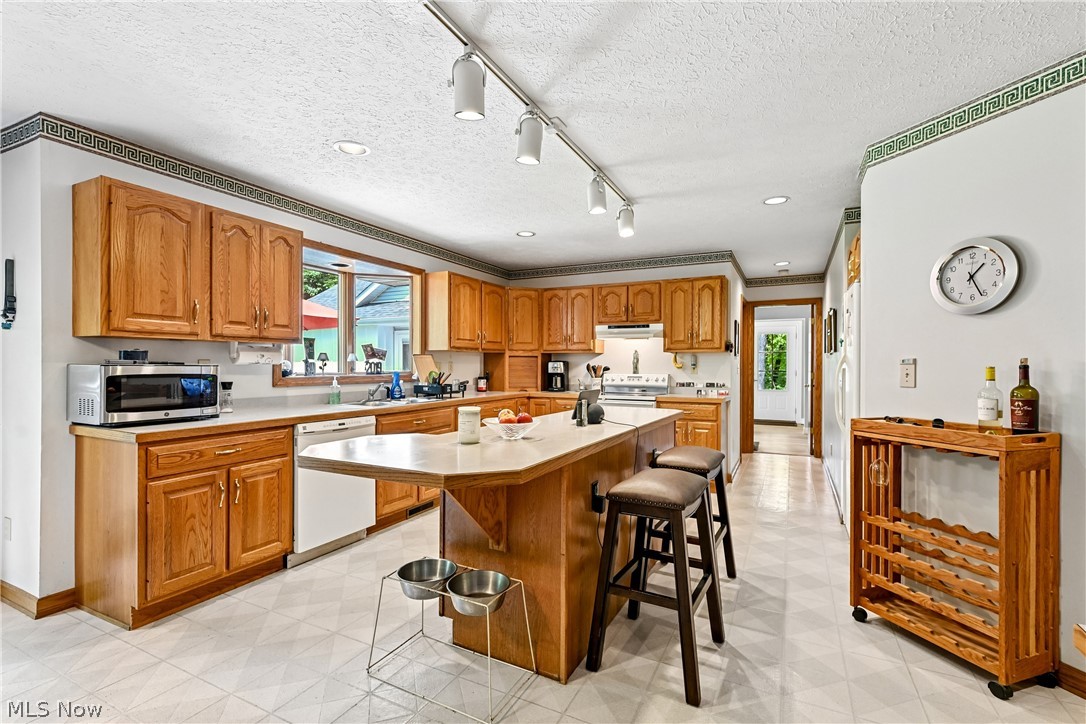 2660 South Medina Line Road Wadsworth, OH 44281 - Photo 12 of 48 Expansive eat-in kitchen featuring a center island with breakfast bar, sink, appliances, wood cabinetry, plenty of counterspace, recessed & track lighting, and LVT flooring