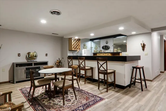 a kitchen with stainless steel appliances kitchen island granite countertop a dining table chairs and a refrigerator