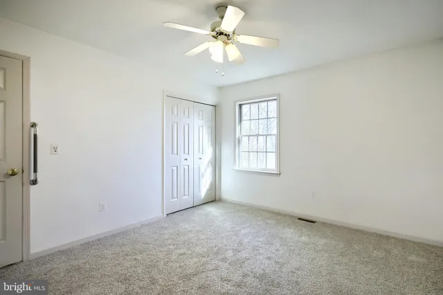 an empty room with windows and ceiling fan