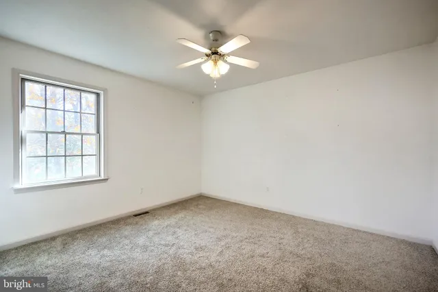 an empty room with a window and a fan