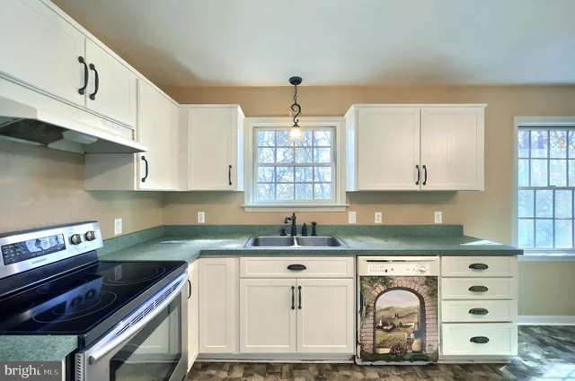 a kitchen with granite countertop a sink a stove and cabinets