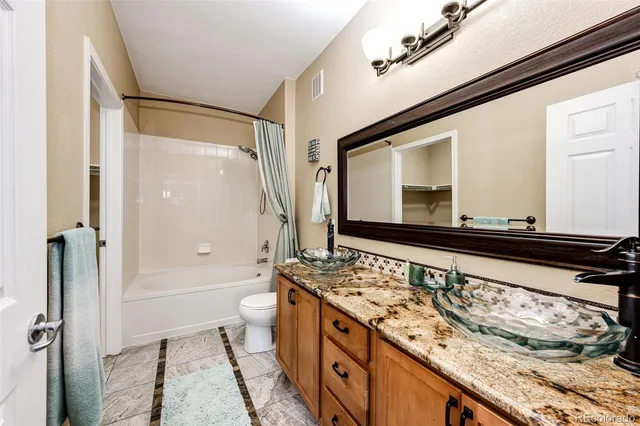 a bathroom with a granite countertop sink mirror vanity and toilet