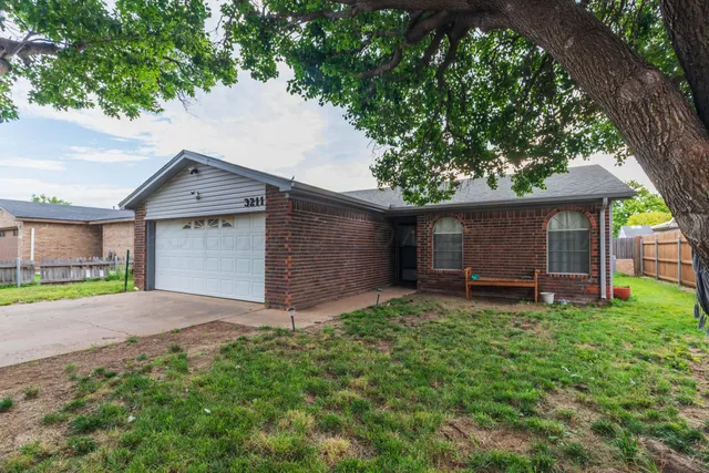 a front view of a house with a yard and a large tree