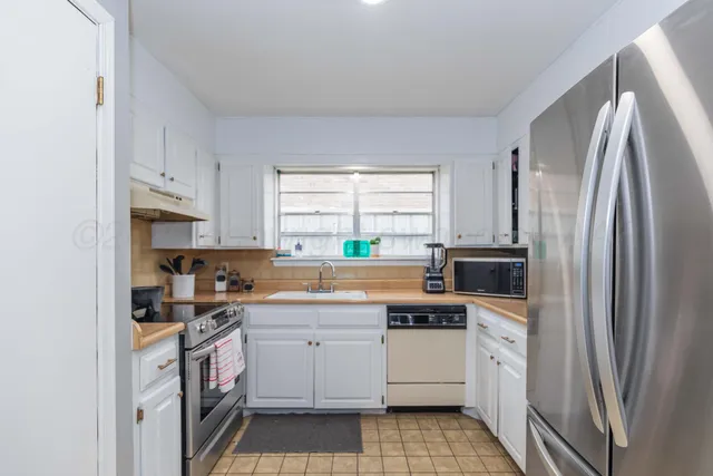 a kitchen with white cabinets sink and stainless steel appliances