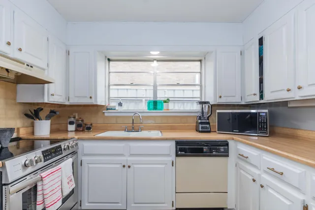a kitchen with granite countertop a sink a stove a microwave and cabinets