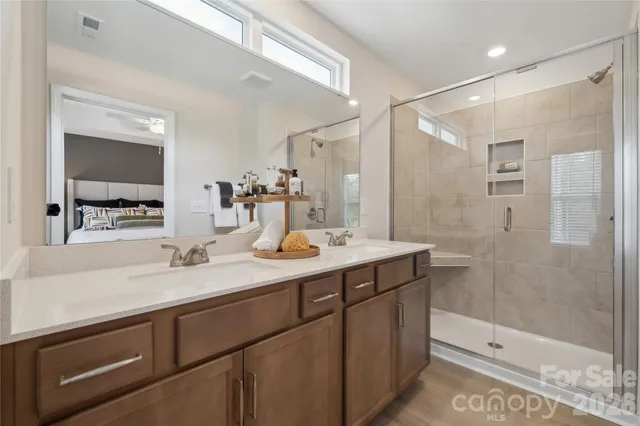 a bathroom with a sink double vanity granite tub shower and a mirror