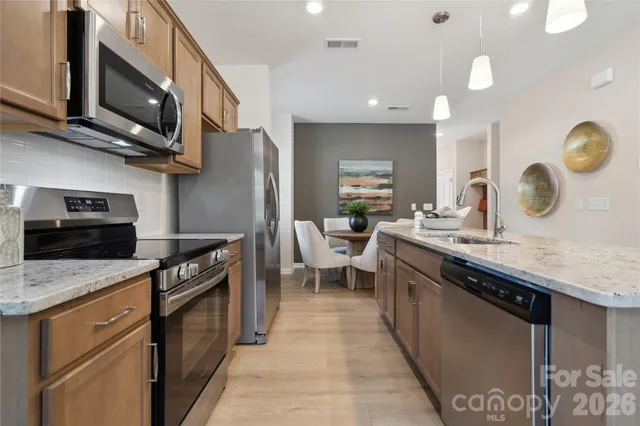 a kitchen with stainless steel appliances granite countertop a sink a stove top oven and a refrigerator