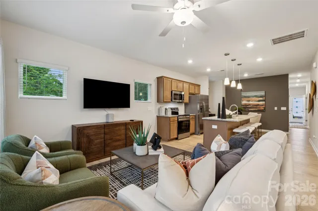 a living room with furniture kitchen view and a flat screen tv
