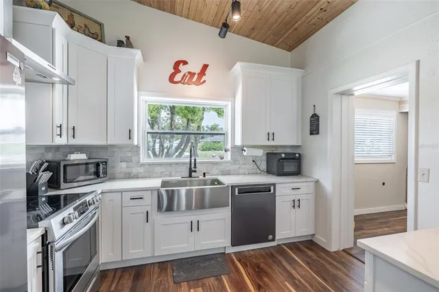 a kitchen with granite countertop a sink stainless steel appliances and cabinets