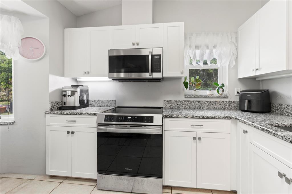 5910 Bella Road Parrish, FL 34219 - Photo 10 of 57 a kitchen with stainless steel appliances granite countertop a stove a microwave a sink and cabinets