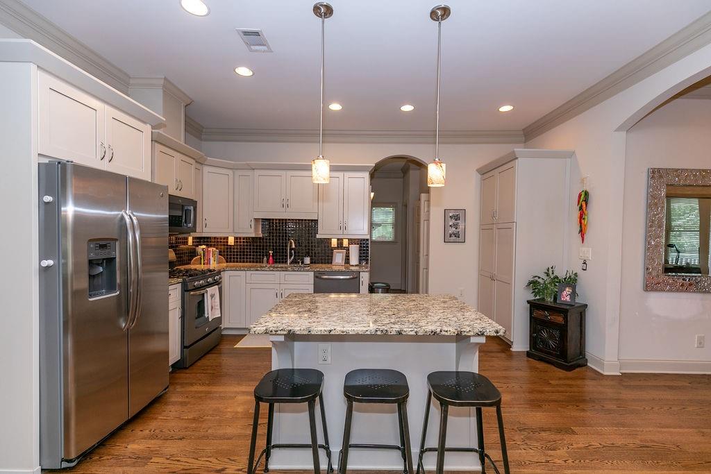 1084 Sanders Avenue Southeast, Unit AB Atlanta, GA 30316 - Photo 17 of 76 a kitchen with granite countertop kitchen island stainless steel appliances a refrigerator a stove a sink a dining table and chairs