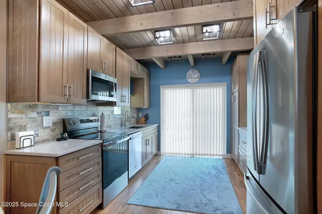 a kitchen with stainless steel appliances granite countertop a refrigerator a stove and a sink