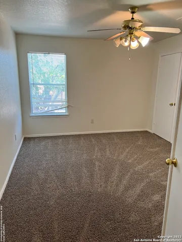 an empty room with a window and a fan