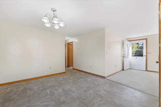 a view of an empty room with a chandelier fan