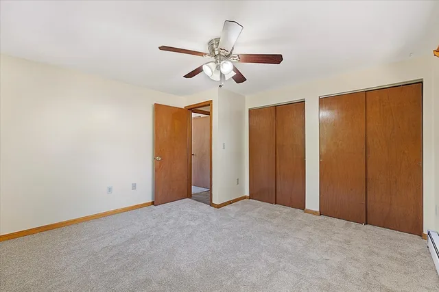 an empty room with a chandelier fan and windows