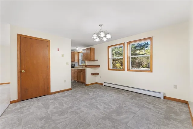 wooden floor in an empty room with a window and a kitchen