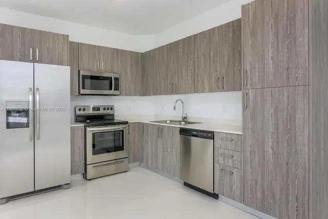a kitchen with stainless steel appliances a stove a sink and a refrigerator