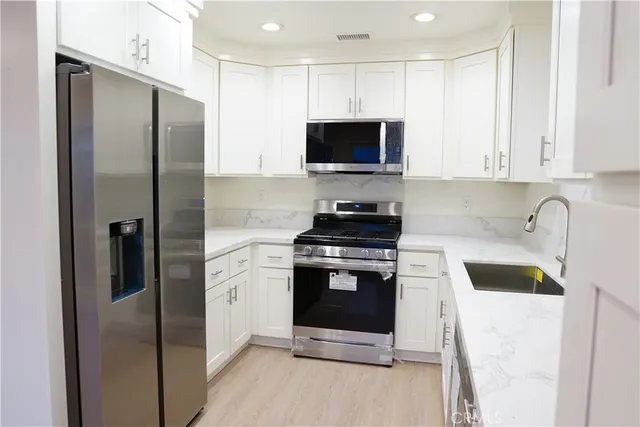 a kitchen with stainless steel appliances a refrigerator sink and microwave