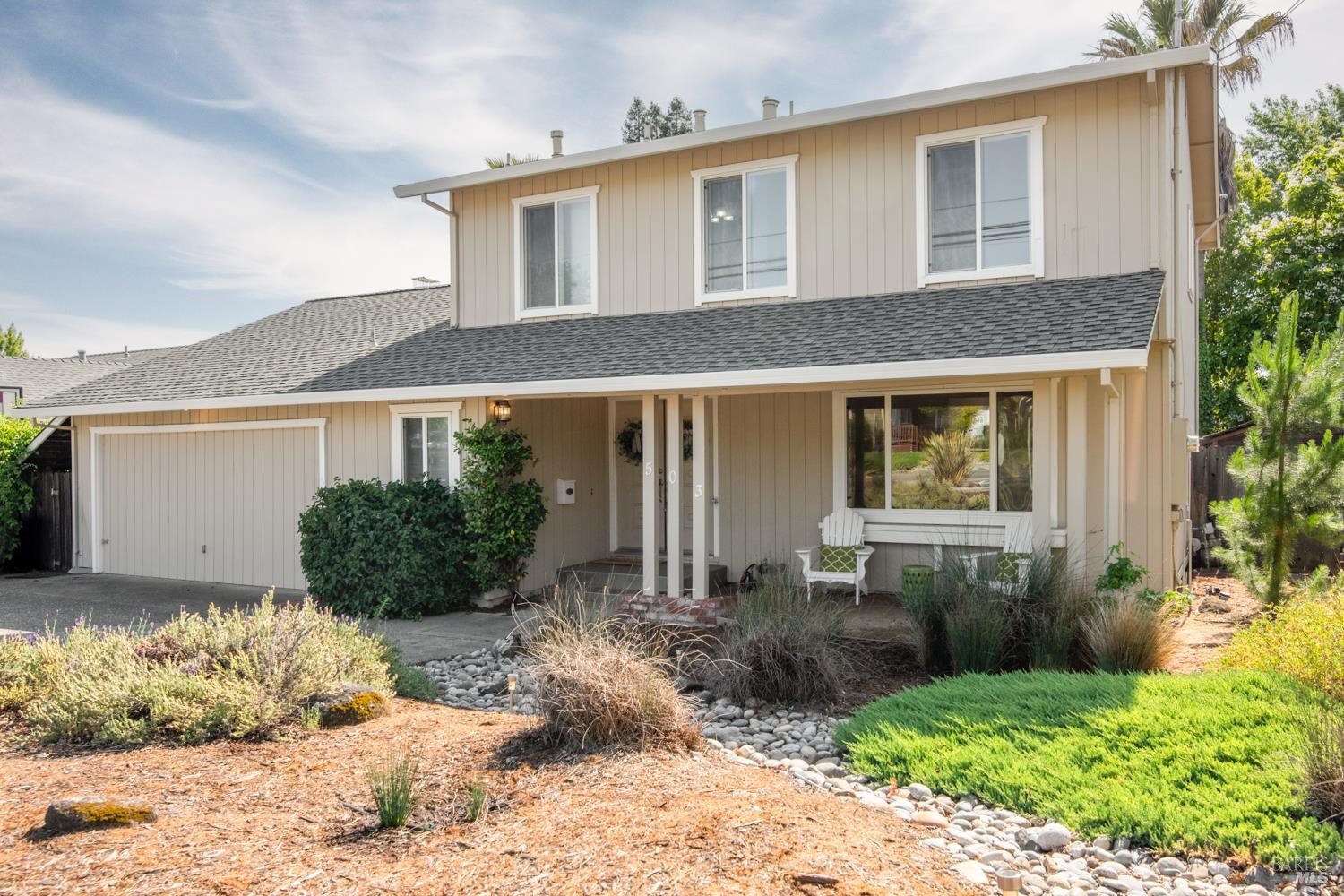 a front view of a house with a yard and potted plants