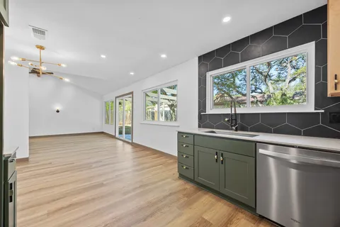 an empty room with wooden floor ceiling fan and window