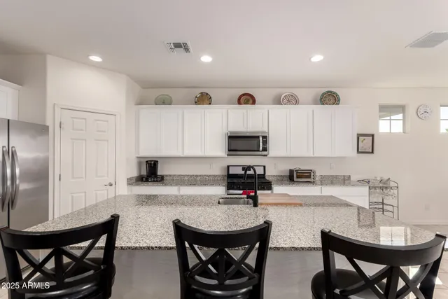 a kitchen with stainless steel appliances a sink a stove a table and chairs