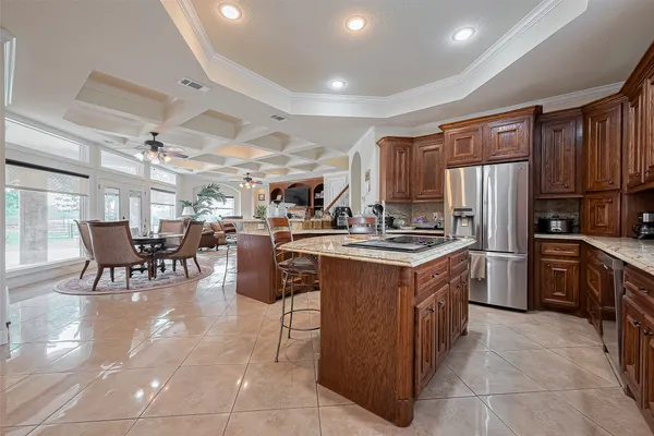 a kitchen with stainless steel appliances granite countertop a table chairs and a refrigerator