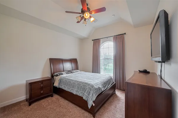 a bedroom with a bed and a flat tv screen on a dresser