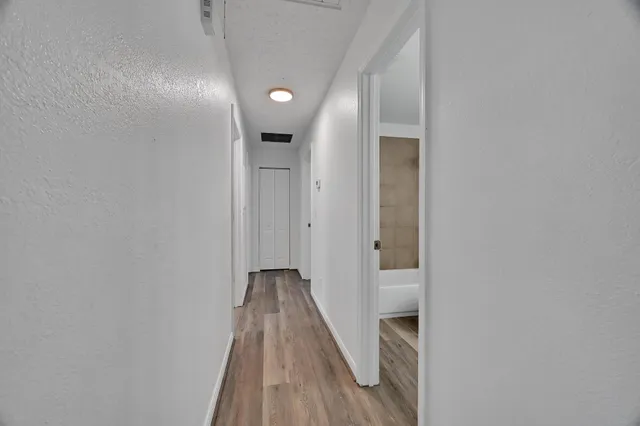 a hallway with wooden floor chandelier and front door