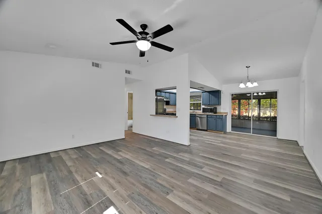 an empty room with wooden floor and a ceiling fan