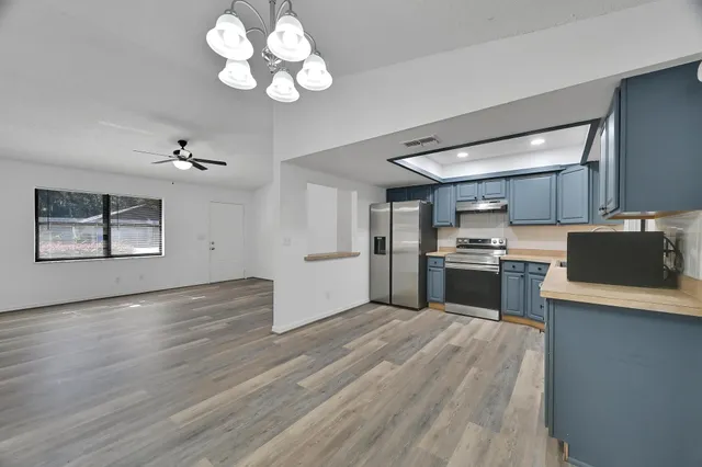 a view of a kitchen with a stove wooden cabinet wooden floor and a chandelier