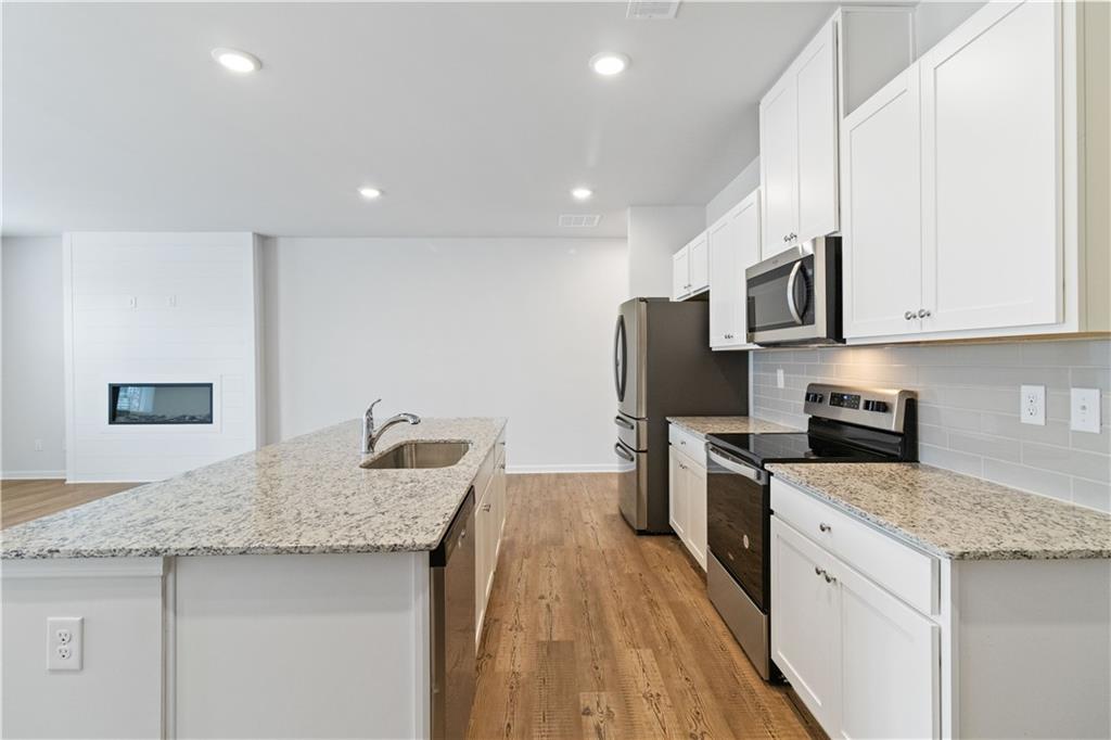 5113 Sidney Sq Drive Flowery Branch, GA 30542 - Photo 16 of 35 a kitchen with stainless steel appliances granite countertop a sink stove and refrigerator