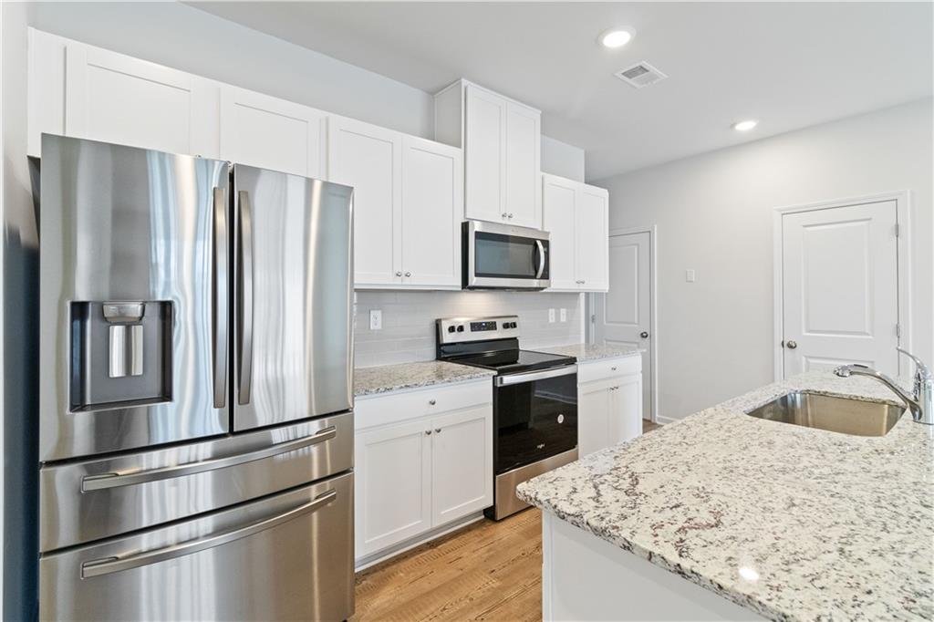 5113 Sidney Sq Drive Flowery Branch, GA 30542 - Photo 17 of 35 a kitchen with kitchen island granite countertop stainless steel appliances and refrigerator