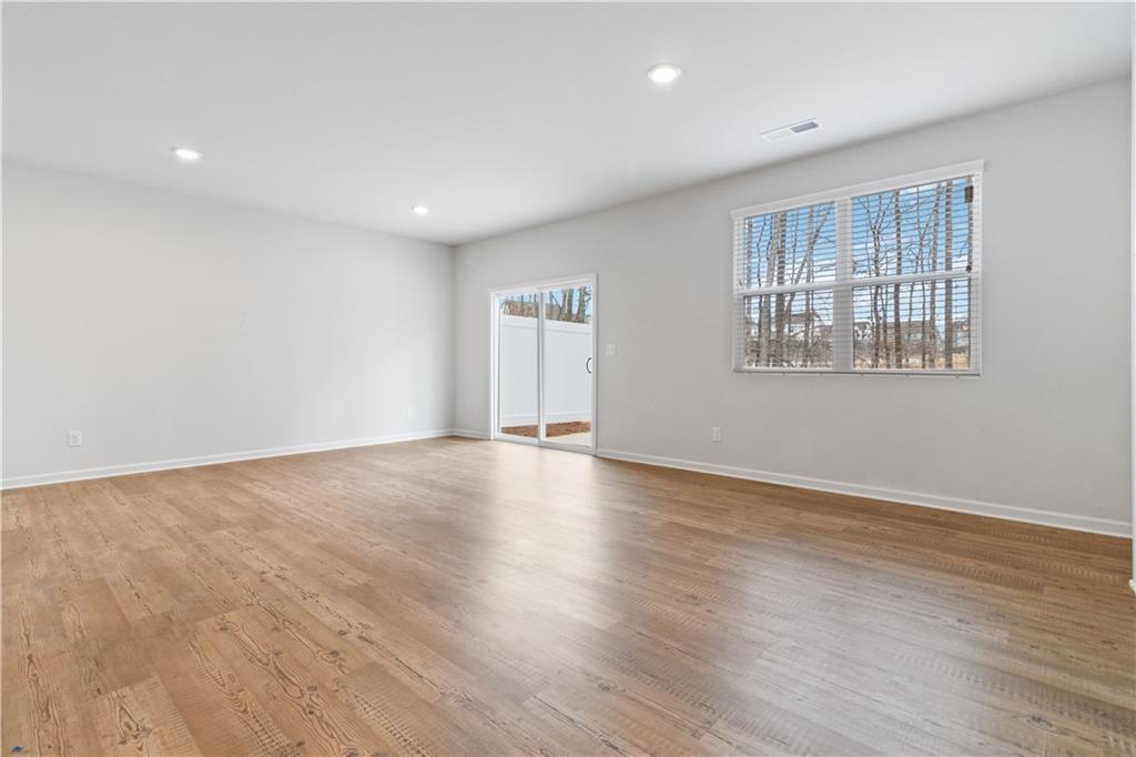 5113 Sidney Sq Drive Flowery Branch, GA 30542 - Photo 7 of 35 an empty room with wooden floor and windows
