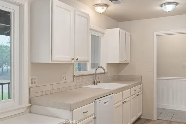 a kitchen with white cabinets and sink
