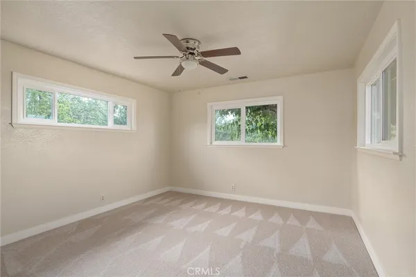 an empty room with a window and a ceiling fan