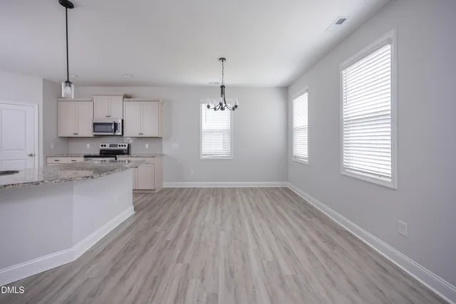 a view of an empty room with wooden floor fireplace and a window