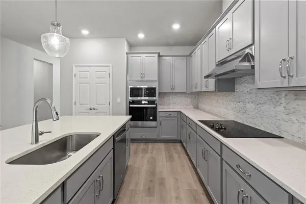 a kitchen with kitchen island granite countertop a sink a counter space appliances and cabinets