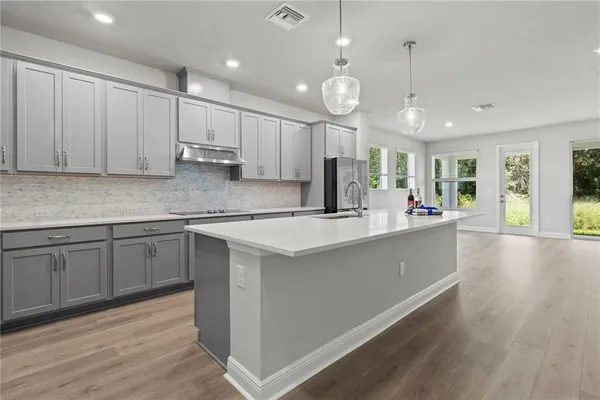 a kitchen with kitchen island granite countertop a sink cabinets and wooden floor