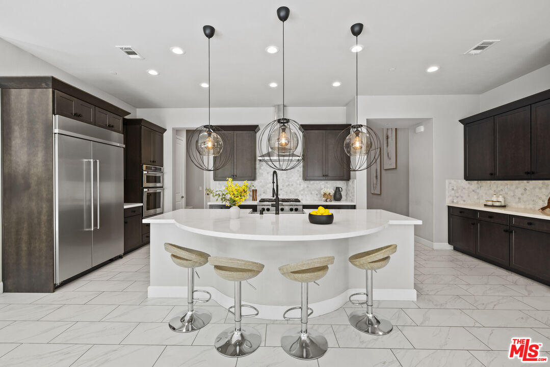 24220 Sterling Ranch Road West Hills, CA 91304 - Photo 12 of 39 a kitchen with stainless steel appliances kitchen island granite countertop a refrigerator a stove a kitchen island a dining table and chairs