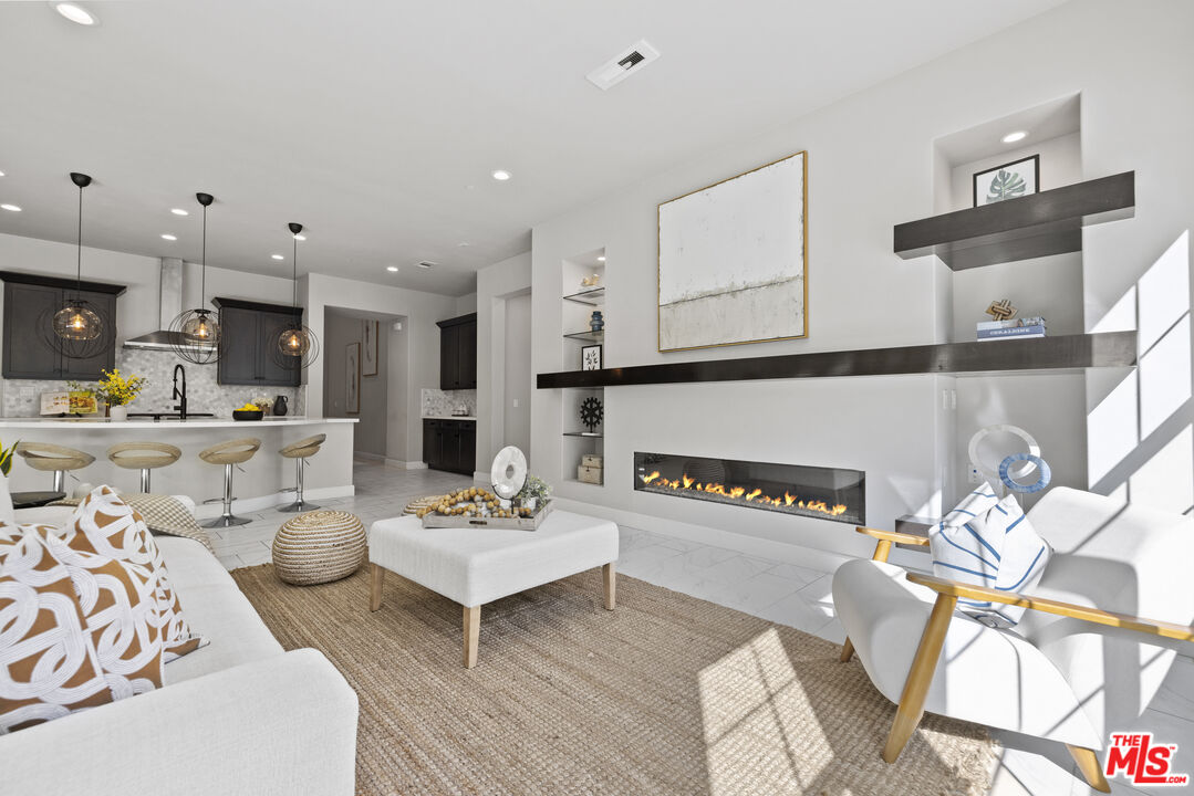 24220 Sterling Ranch Road West Hills, CA 91304 - Photo 2 of 39 a living room with furniture kitchen view and a fireplace