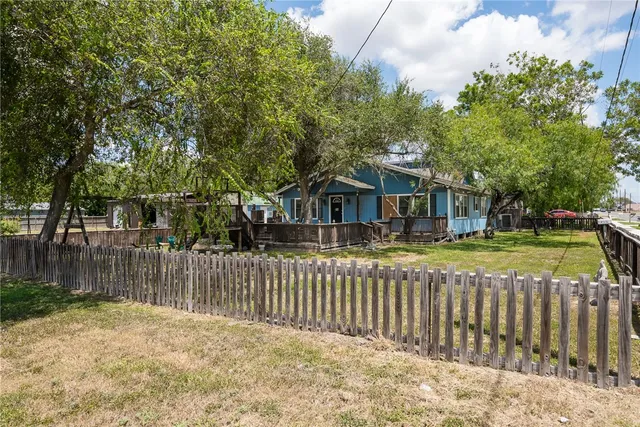 a view of a house with a yard and large tree