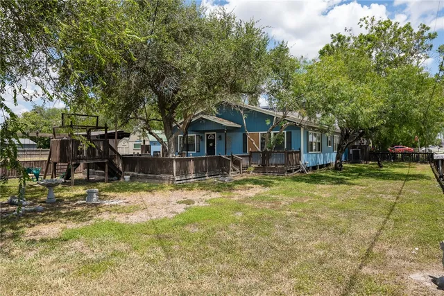 a view of a house with a yard and large tree