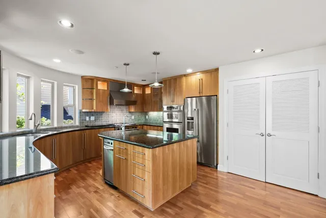 a kitchen with stainless steel appliances granite countertop a sink and a refrigerator