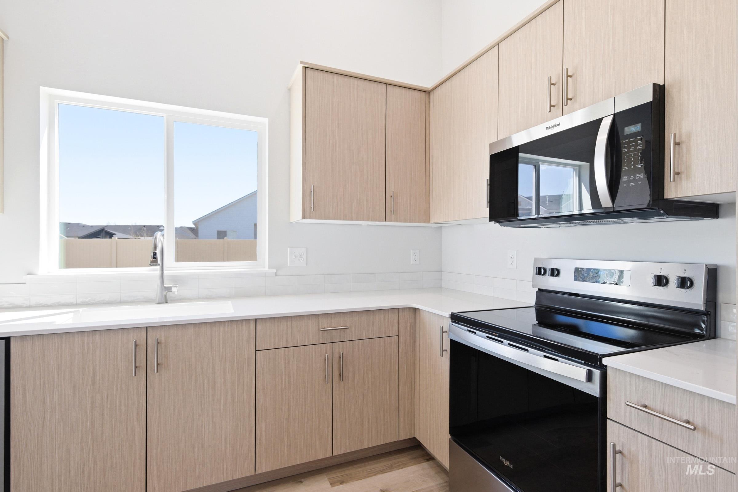 12817 Decatur Street Nampa, ID 83651 - Photo 6 of 19 Kitchen featuring light wood-finish cabinetry with brushed nickel hardware, white countertops, and a white subway tile backsplash